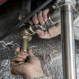 Hands tightening plumbing connections in a utility or inspection setting.