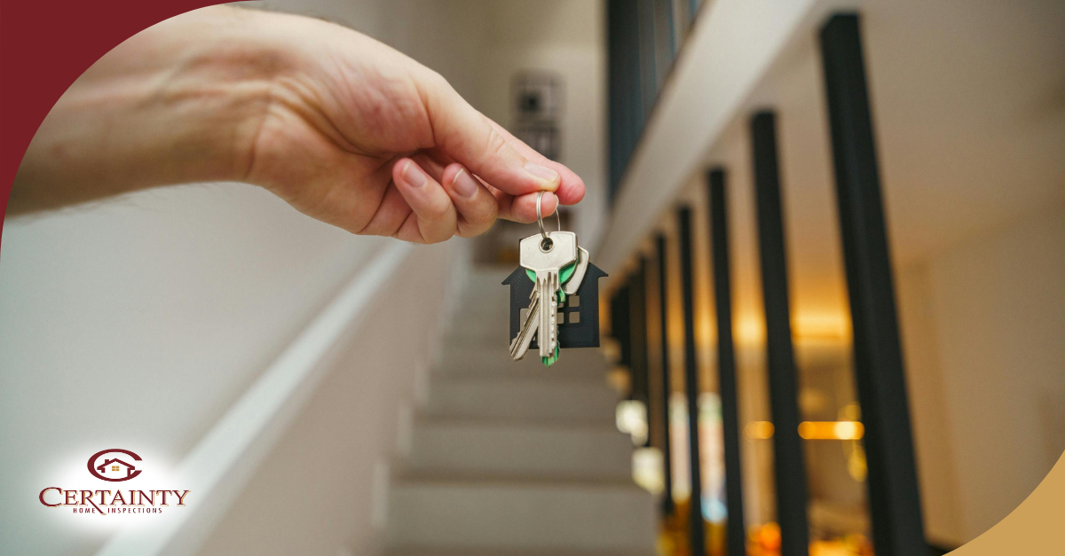 Hand holding house keys inside a home.